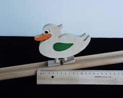 A wooden duck on a ruler Description automatically generated