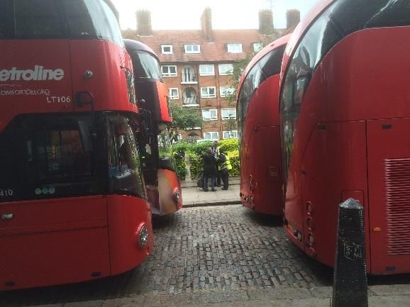 A group of red buses parked on a street Description automatically generated