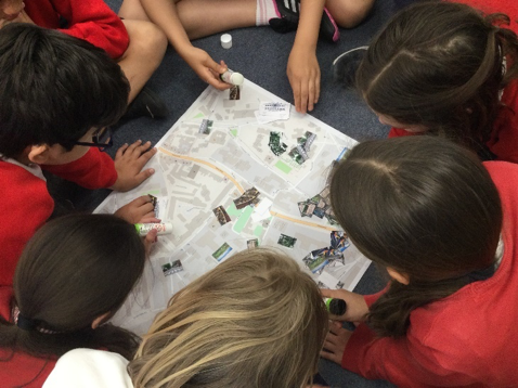 A group of children looking at a map Description automatically generated