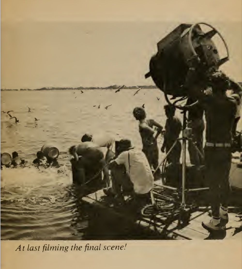 A behind the scenes photo of Spielberg and crew filming Dreyfuss and Scheider using the barrels to kick their way back to land, from the book ON LOCATION ON MARTHA’S VINEYARD. The caption reads, “At last filming the final scene!”