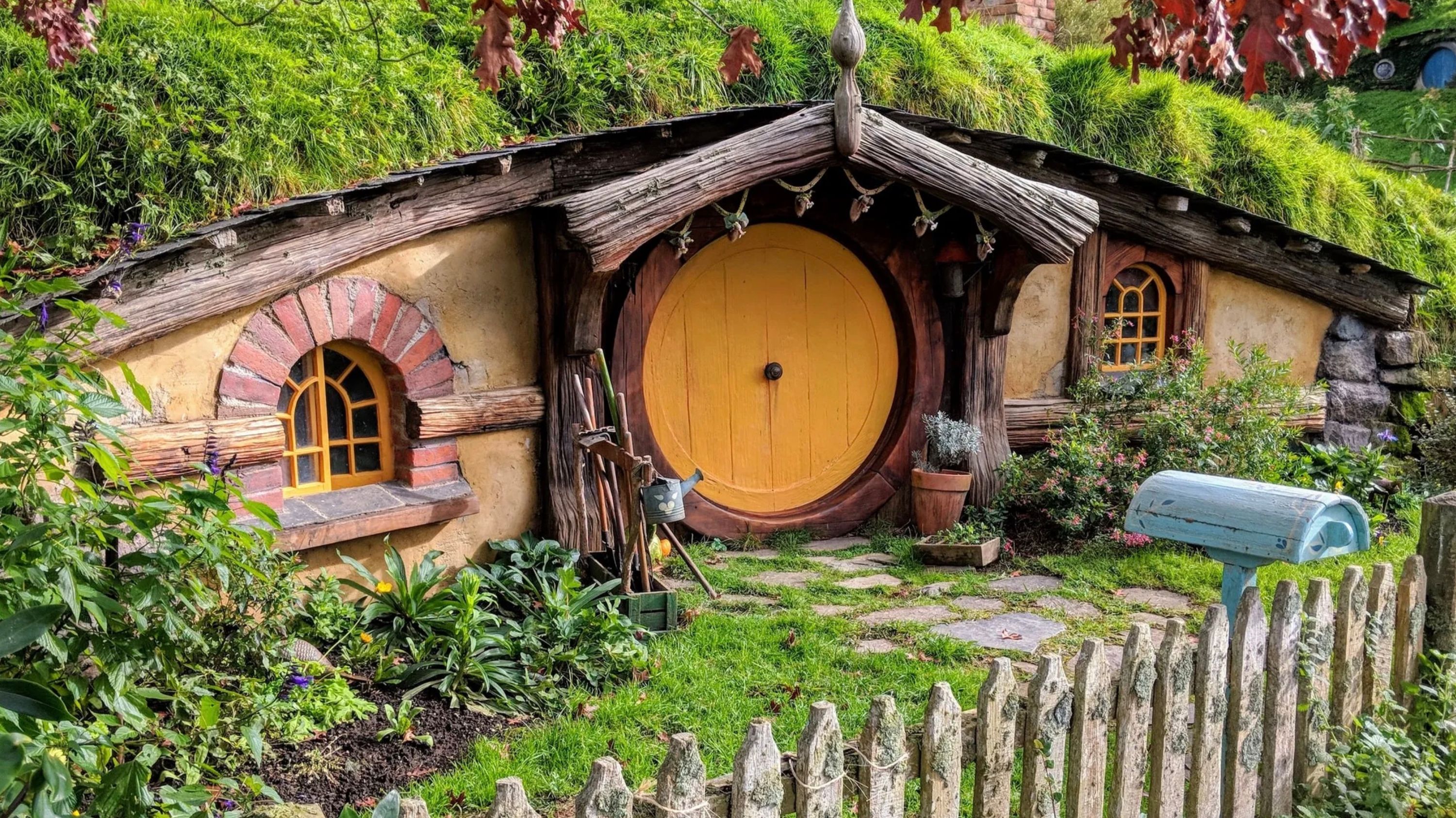 Hobbit house at Hobbiton in New Zealand. A round door in a house set into a hillside, with grass on the roof