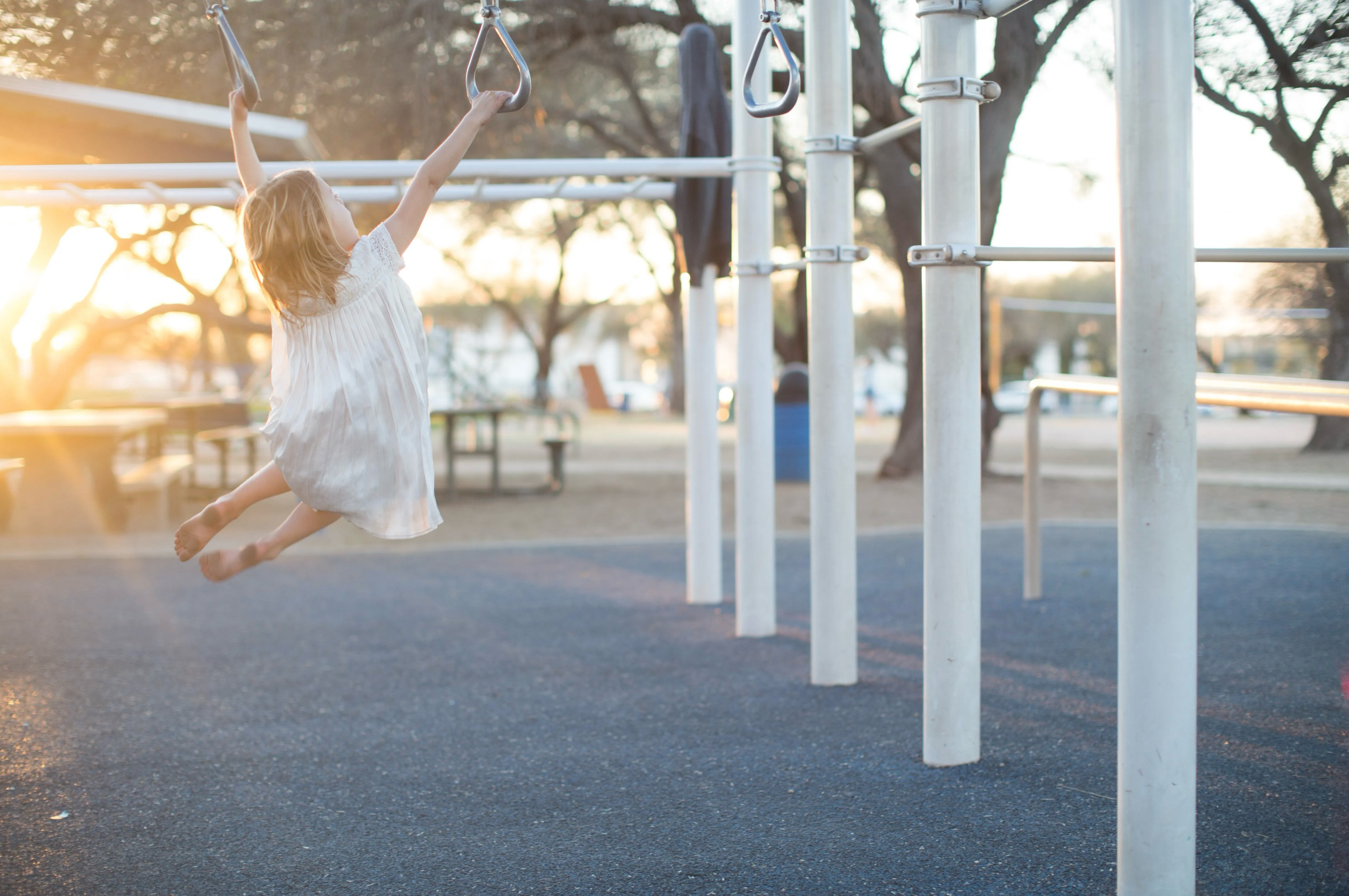 Girl playing in a playground, with a ray of golden sun coming in from the left of the image