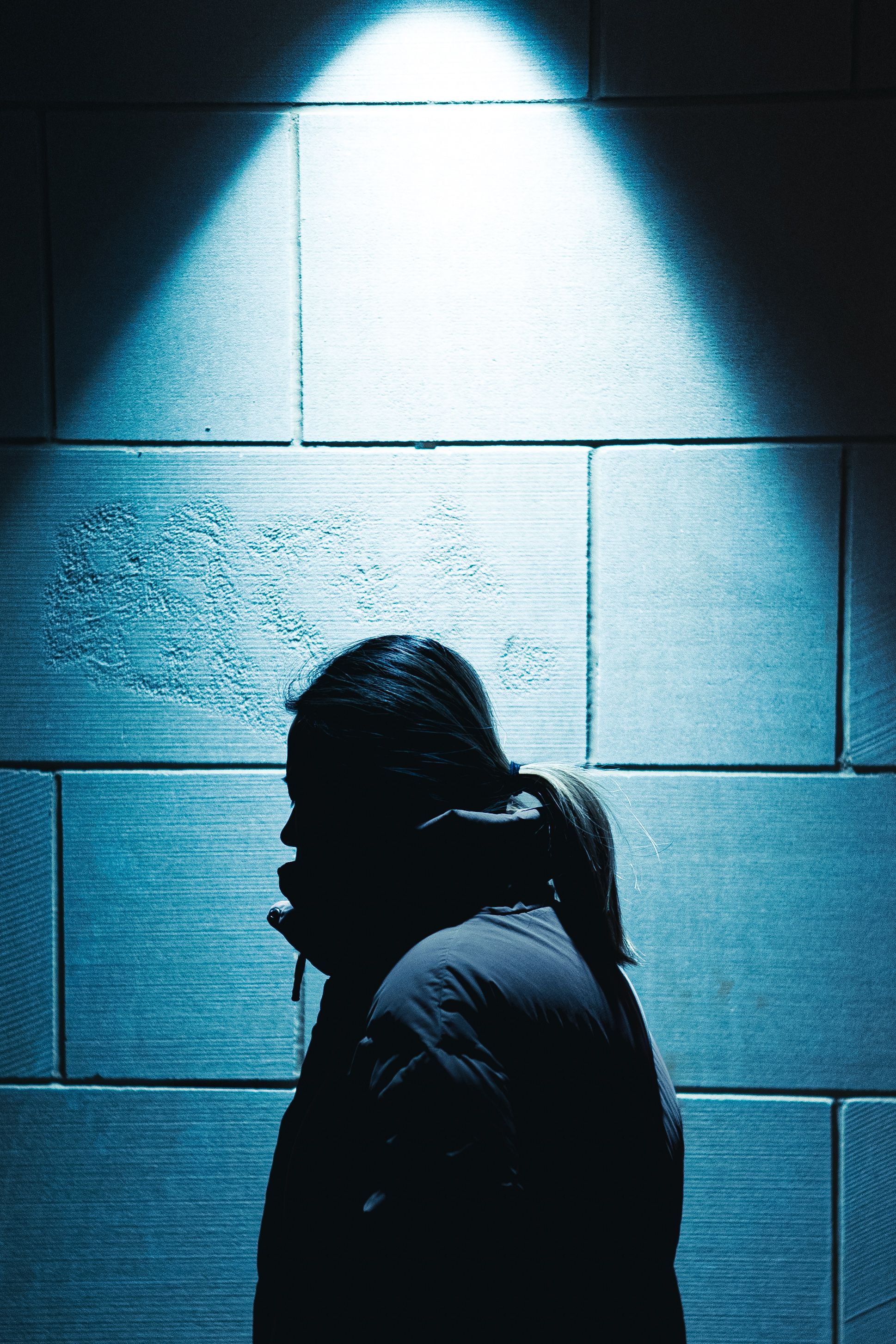 A pedestrian in silhouette under a streetlight at night