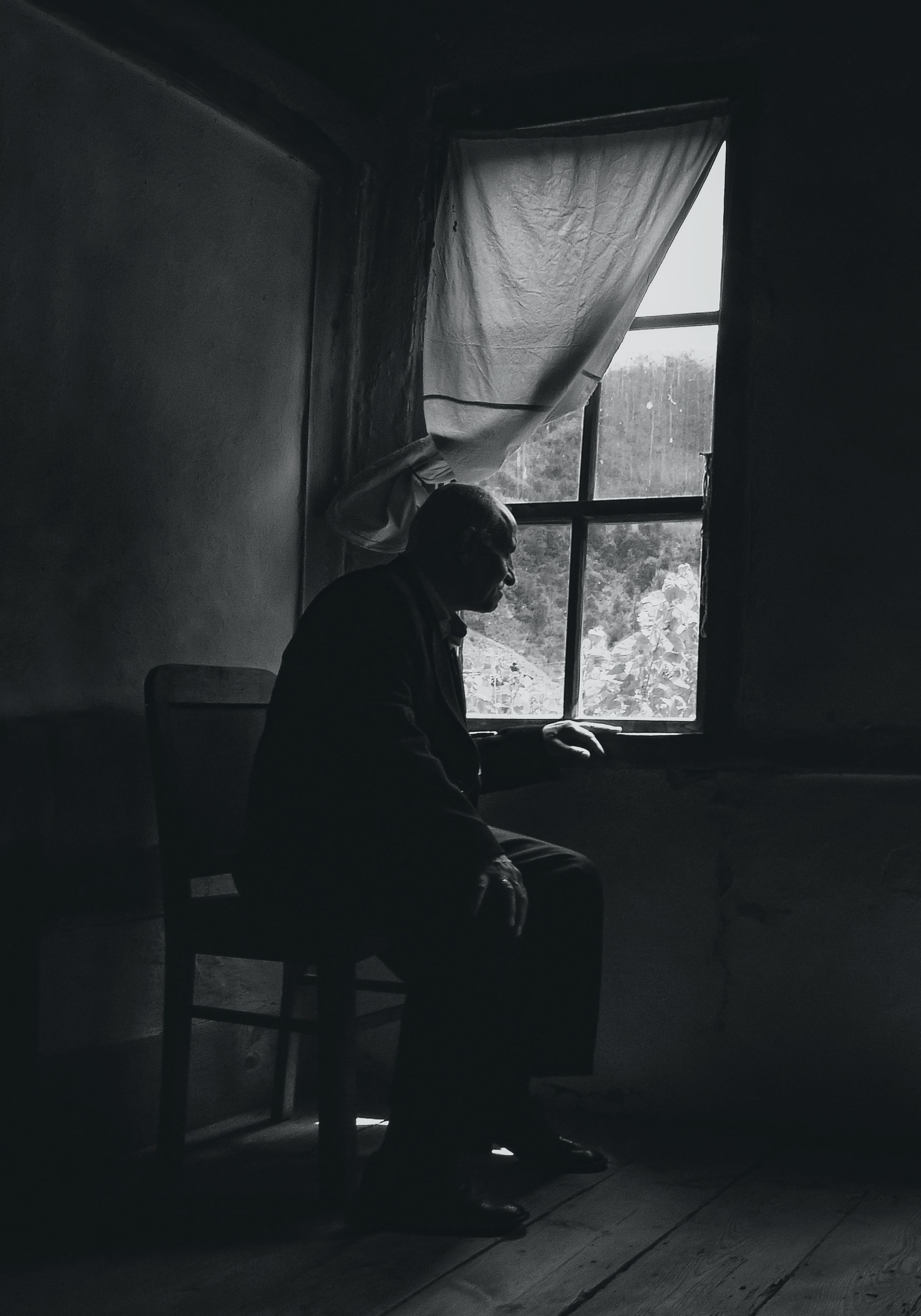 Photo of an old man sitting by a window