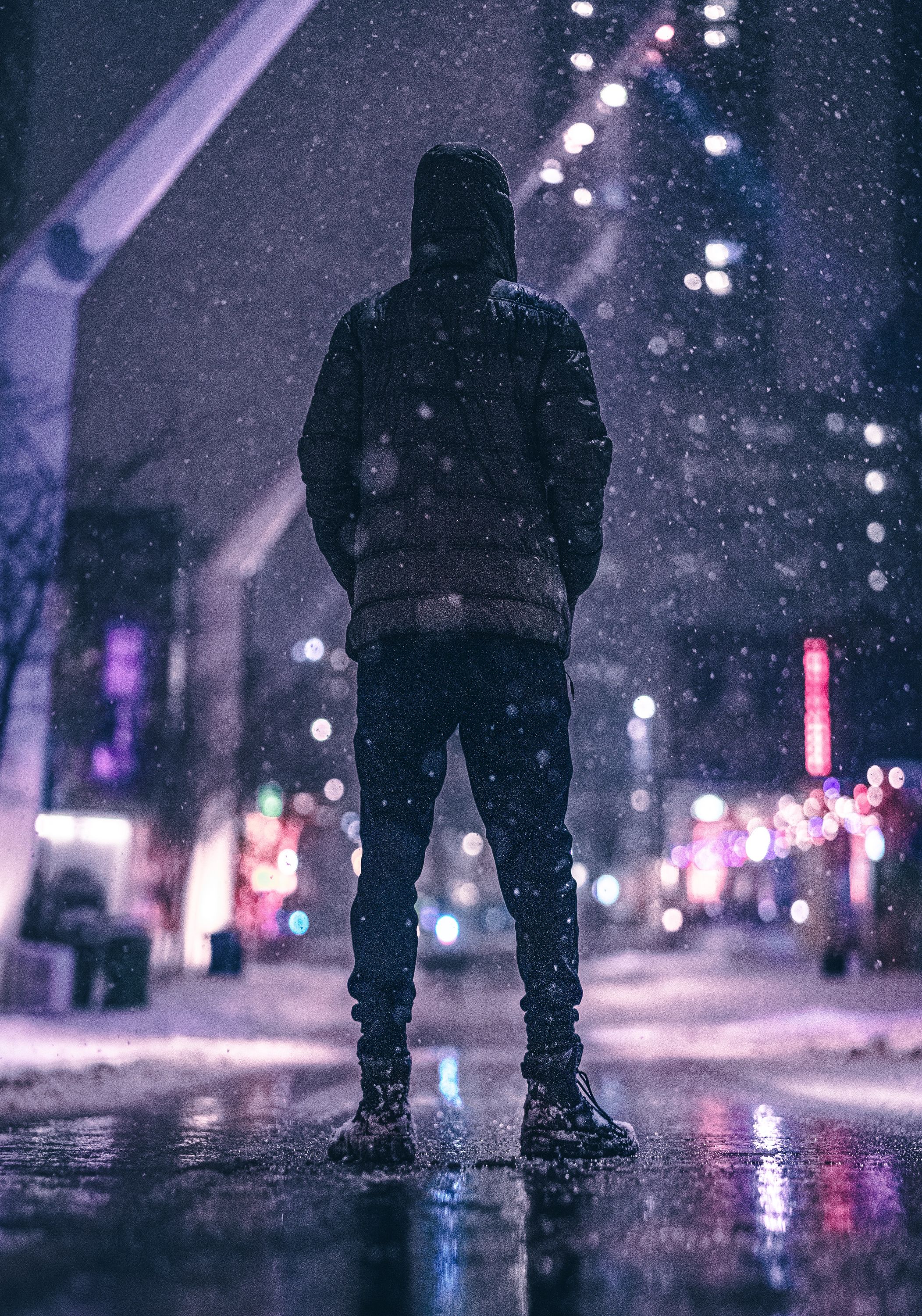 Photo of a man standing in snow at night in the middle of a street