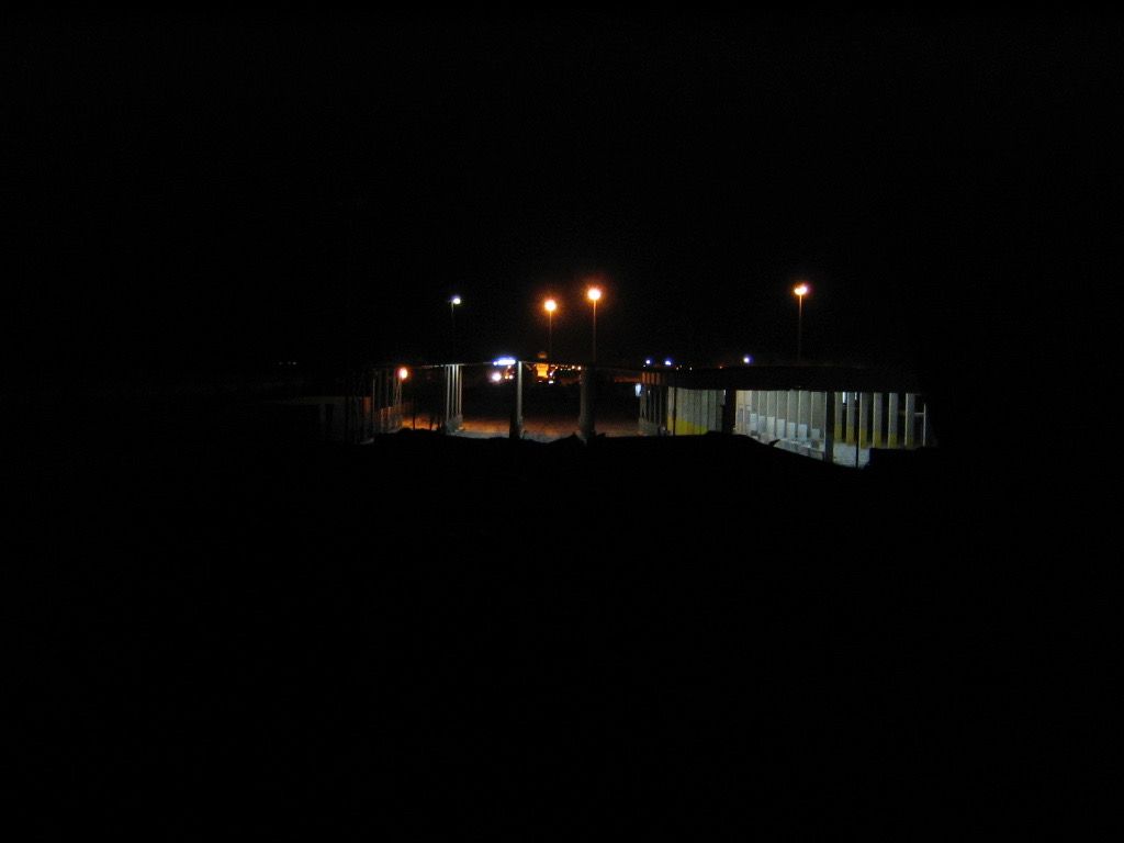 Looking toward the Jordanian border, marked by the lights just beyond the structure in the middle ground, at night.