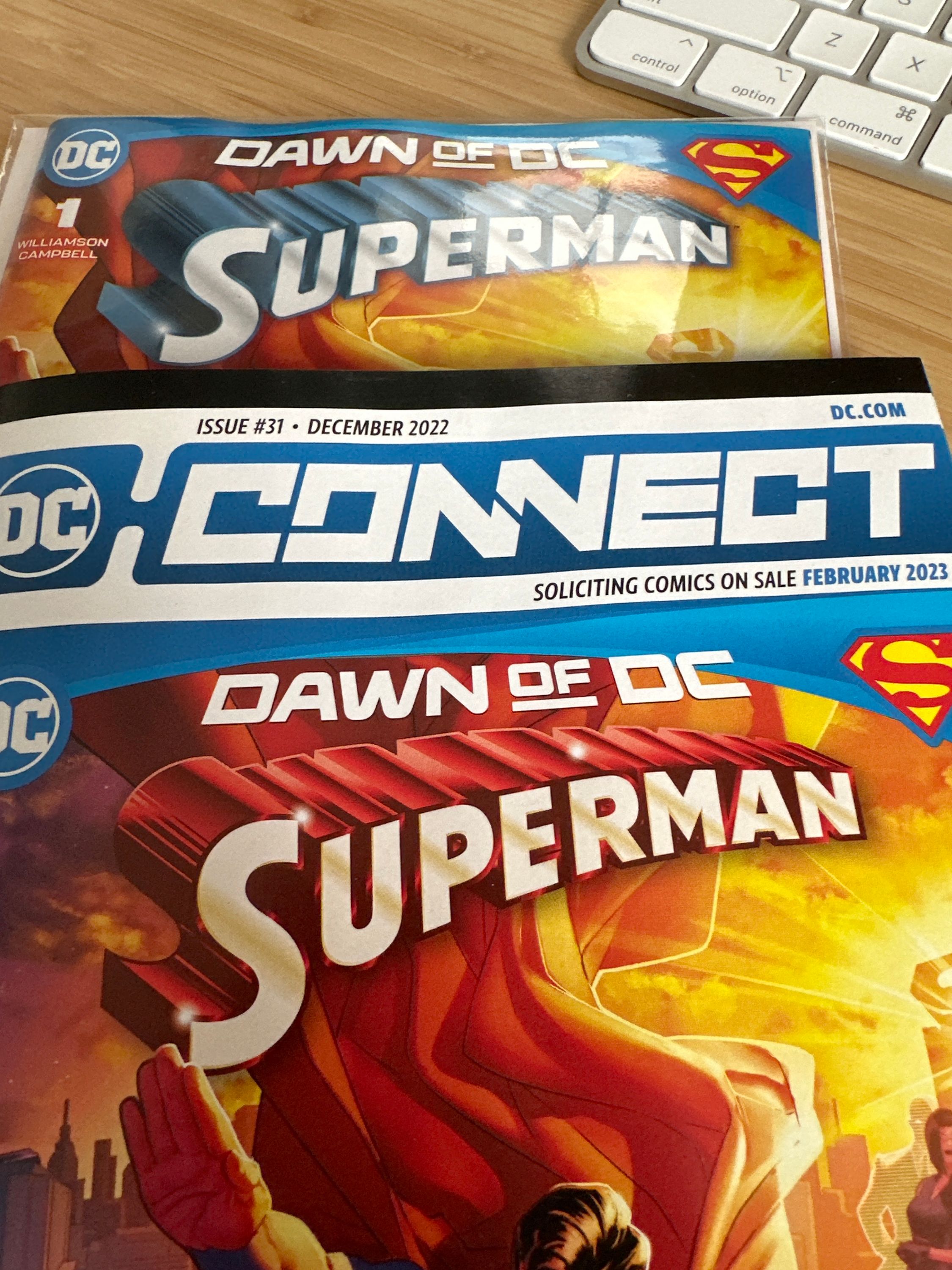 the latest Superman #1 along with the DC connect issue promoting it, each with different Superman logos.