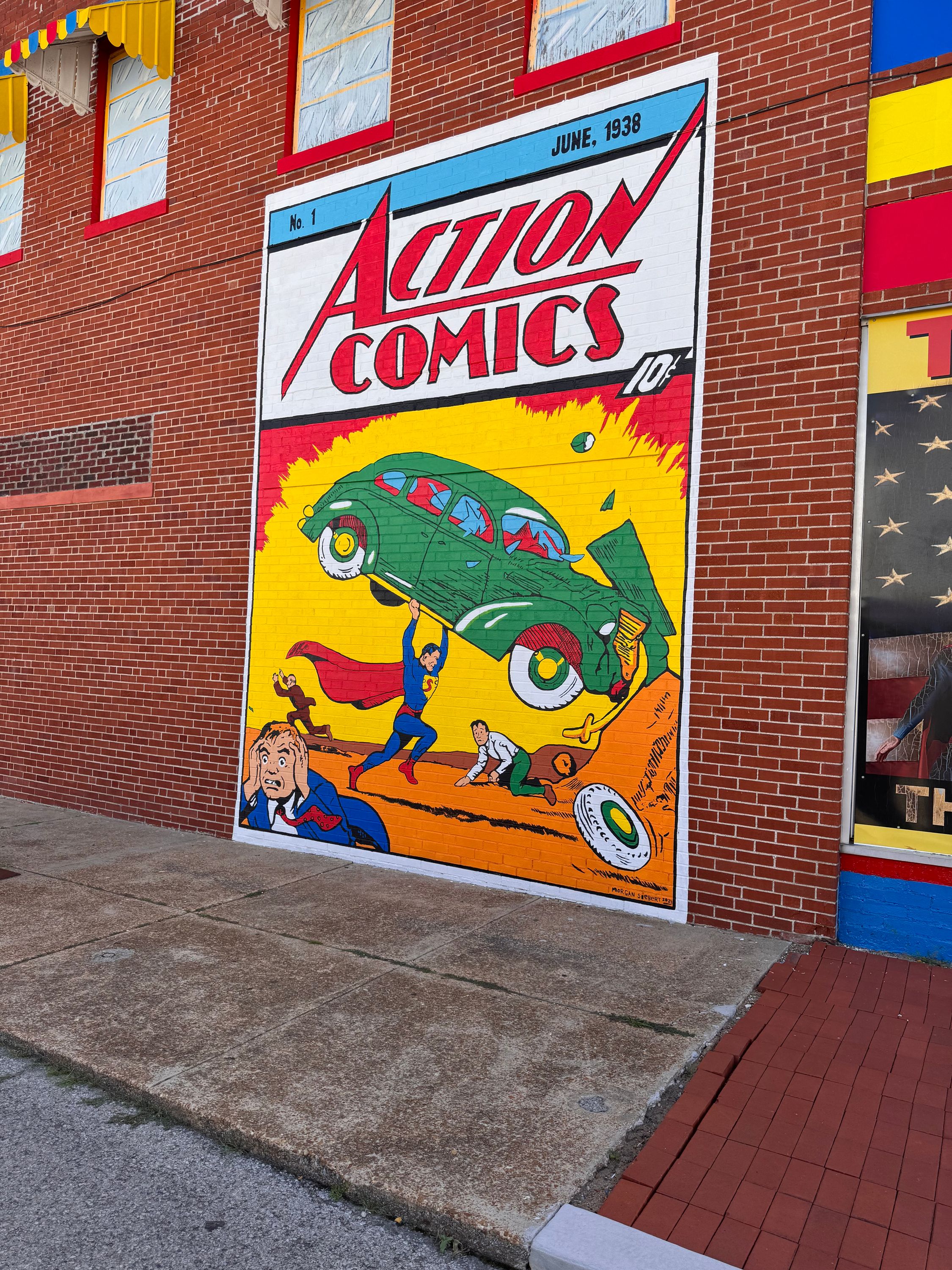 A mural of Action Comics #1 on the side of the Super Museum. It depicts Superman smashing a green sedan with the occupants running away scared