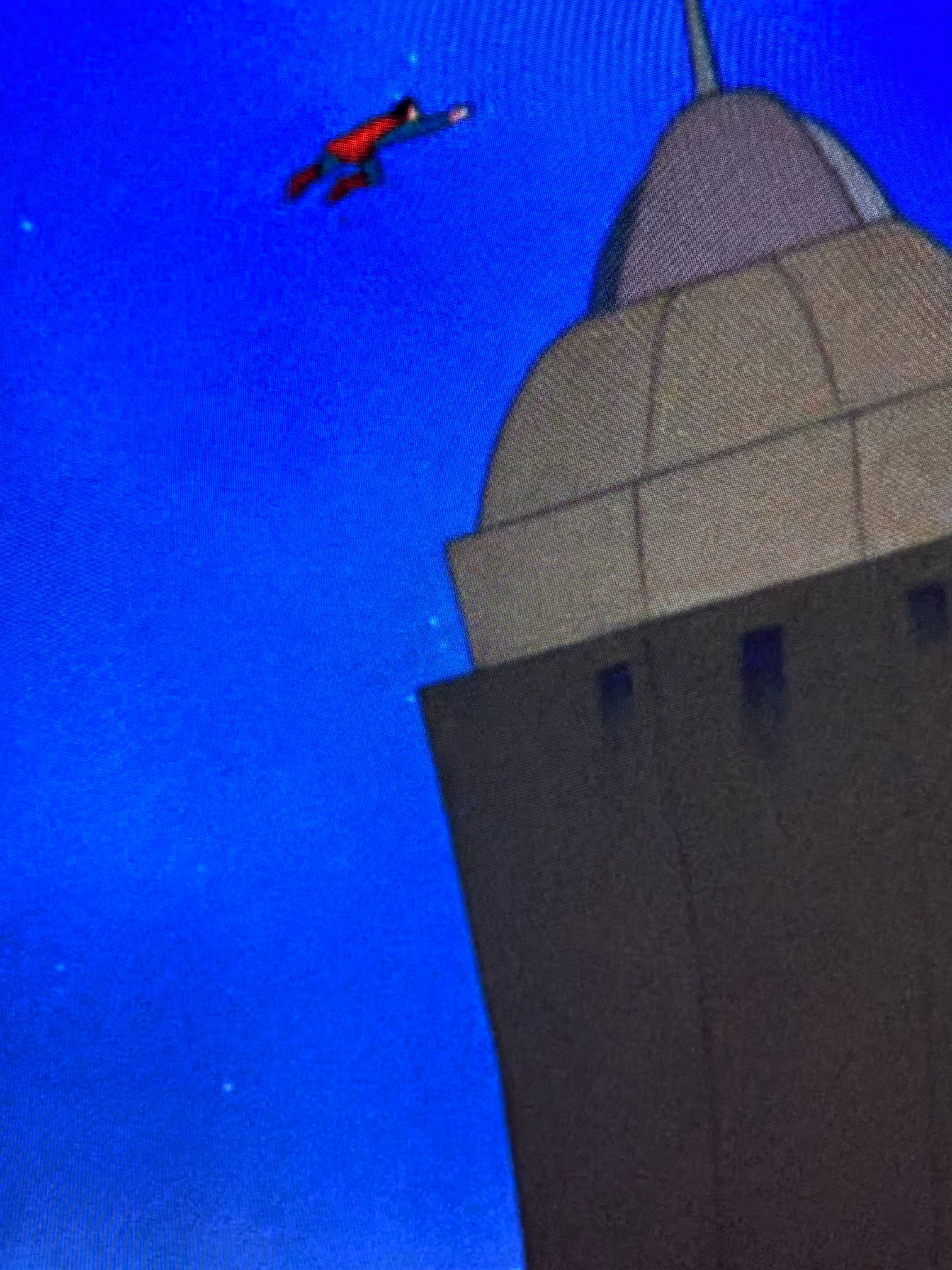 A close up of Superman straightening out a building that was close to falling over. on the left side of the building you can see a halo around the building due to edge enhancement.