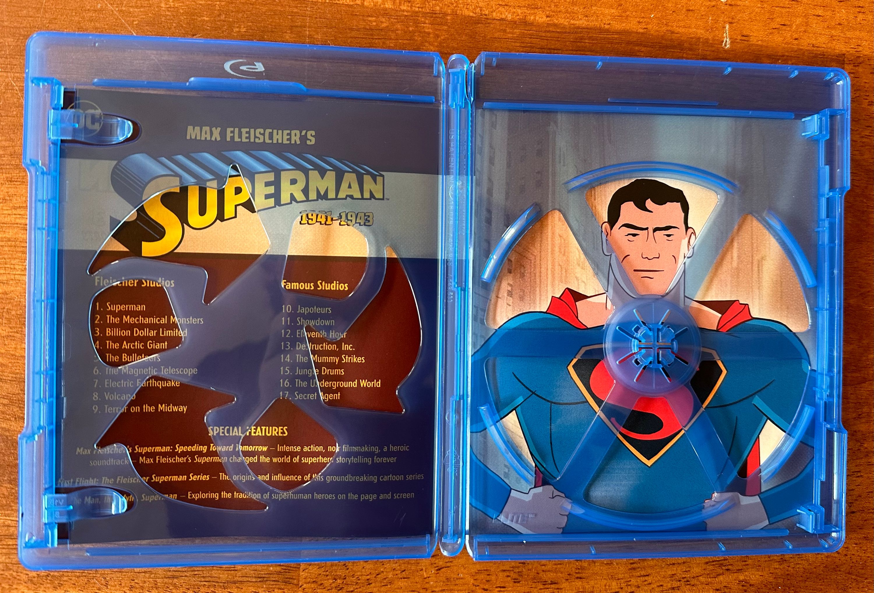 Inside the blu-ray release. Text includes list of episodes: Fleischer Studios 1. Superman 2. The Mechanical Monsters 3. Billion Dollar Limited 4. The Arctic Giant 5. The Bulleteers 6. The Magnetic Telescope 7. Electric Earthquake 8. Volcano 9. Terror on the Midway. Famous Studios 10. Japoteurs 11. Showdown 12. Eleventh Hour 13. Destruction, Inc. 14. The Mummy Strikes 15. Jungle Drums 16. The Underground World 17. Secret Agent SPECIAL FEATURES Superman: Speeding Toward Tomorrow - Intense action, noir filmmaking, a heroic soundtrack Max Fleischer’s Superman changed the world of superhero, storytelling forever. First Flight: The Fleischer Superman Series - The origins and influence of this groundbreaking cartoon series. The Man, the Myth, Superman - Exploring the traction of superhuman heroes on the page and screen. On the right there is an image of Superman in front of a city street