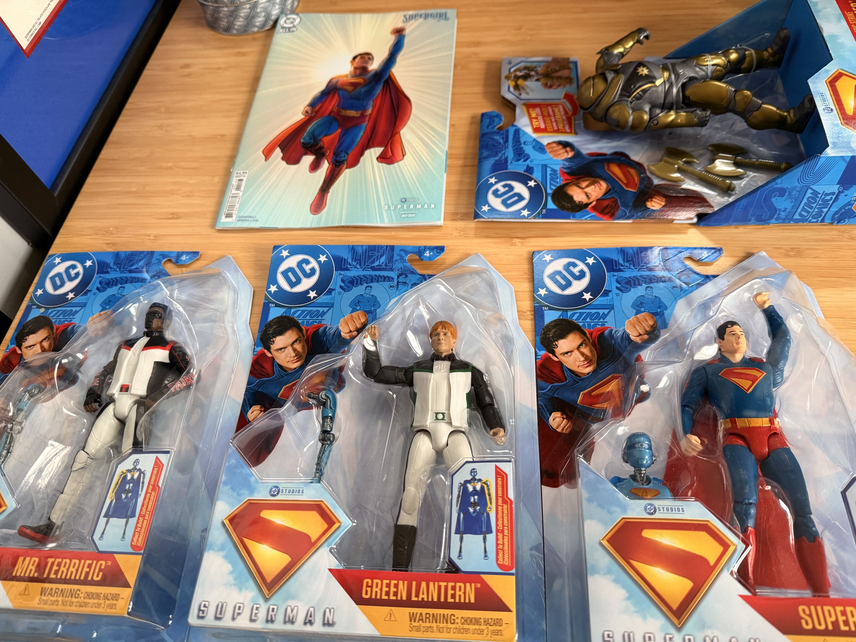 Four new Superman movie action figures and a Superman movie comic book. The action figures are Mr. Terrific, Green Lantern, Superman, and the Hammer.