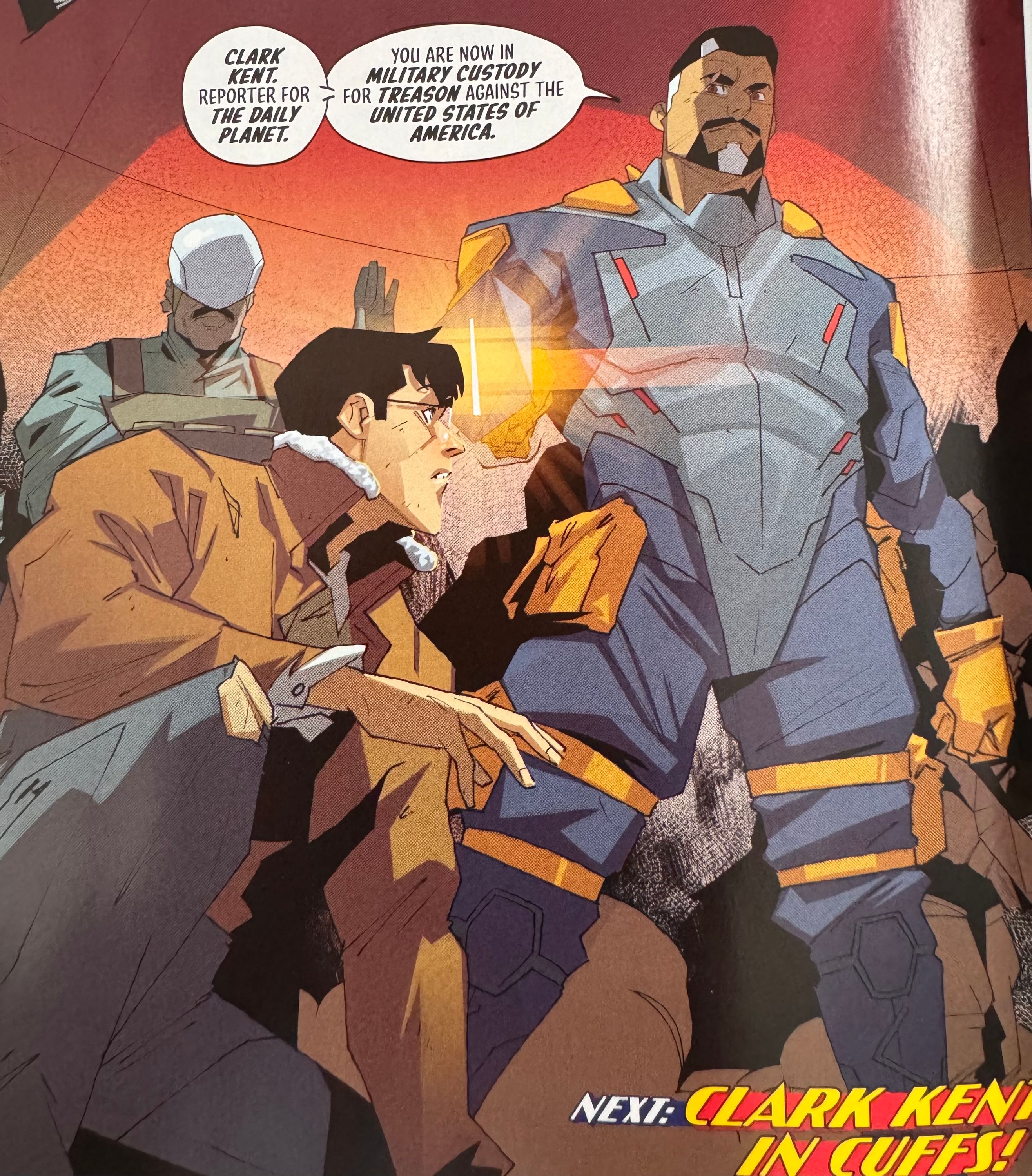 Comic book panel showing Bloodspot holding a gun to Clark. Dialogue reads “CLARK KENT. REPORTER FOR THE DAILY PLANET. YOU ARE NOW IN MILITARY CUSTODY FOR TREASON AGAINST THE UNITED STATES OF AMERICA.” Caption at the bottom reads “Next: Clark Kent in cuffs!”