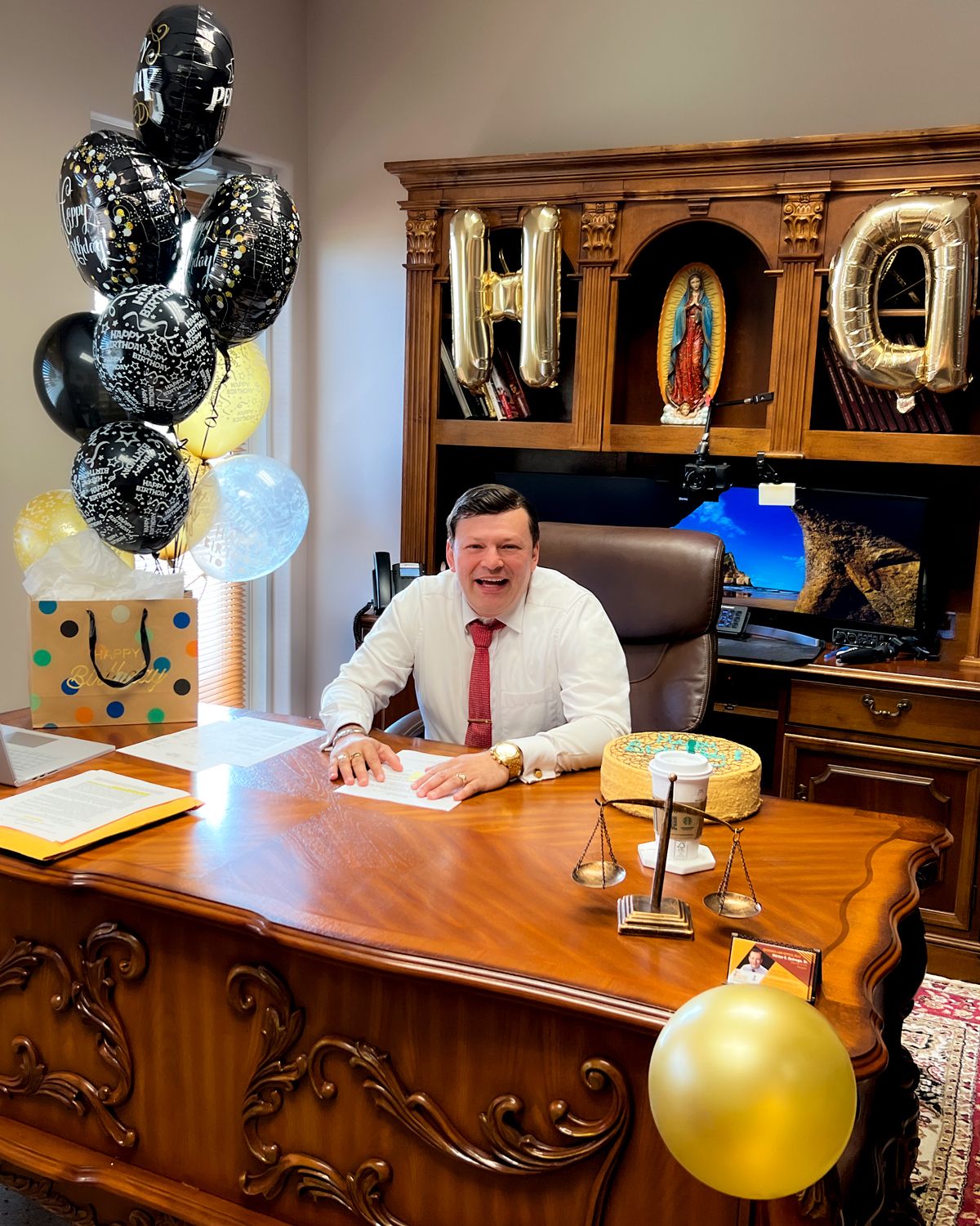 A person sitting at a desk with balloons Description automatically generated