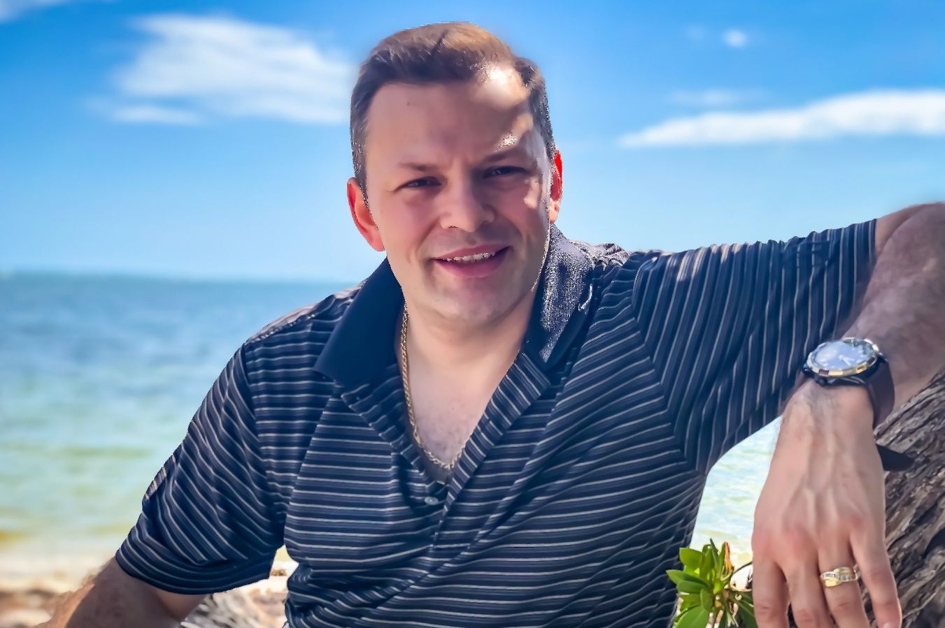 A person sitting on a rock by the water Description automatically generated