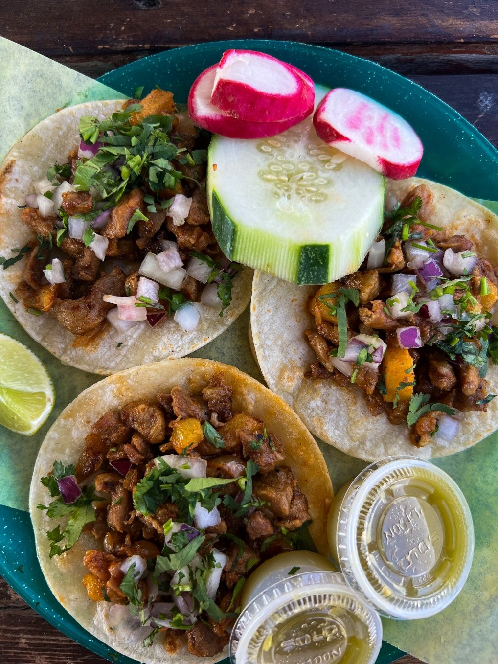 A plate of tacos with vegetables and sauce Description automatically generated