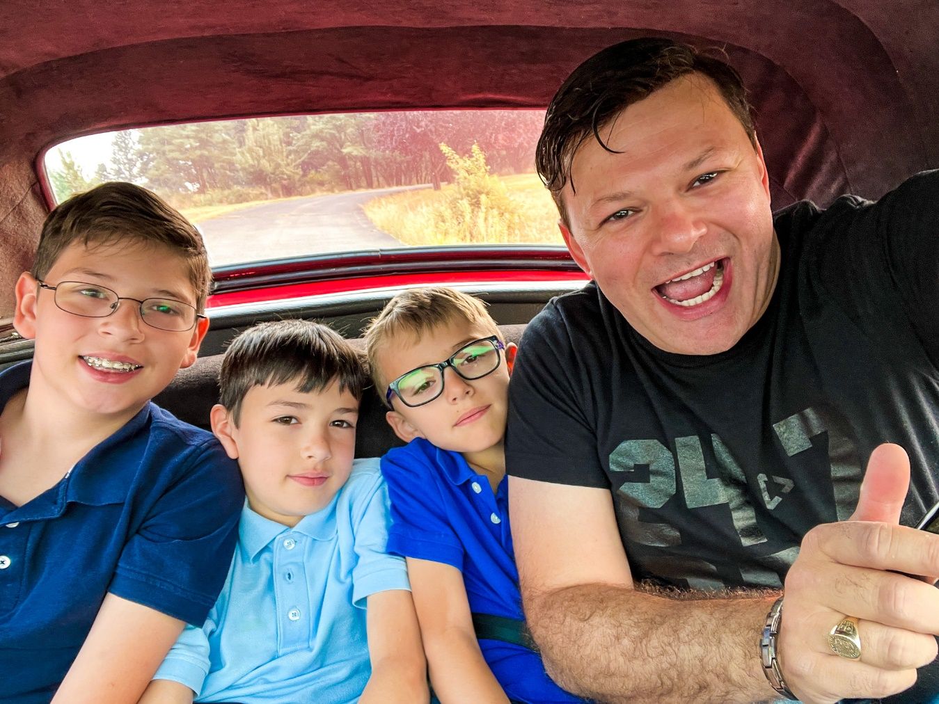 A person and two boys in a car Description automatically generated