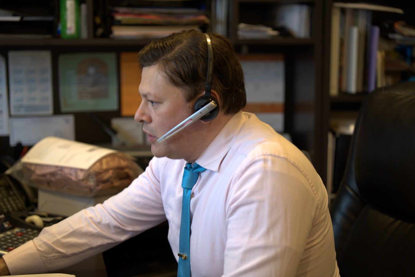 A person wearing a headset and talking on a computer Description automatically generated