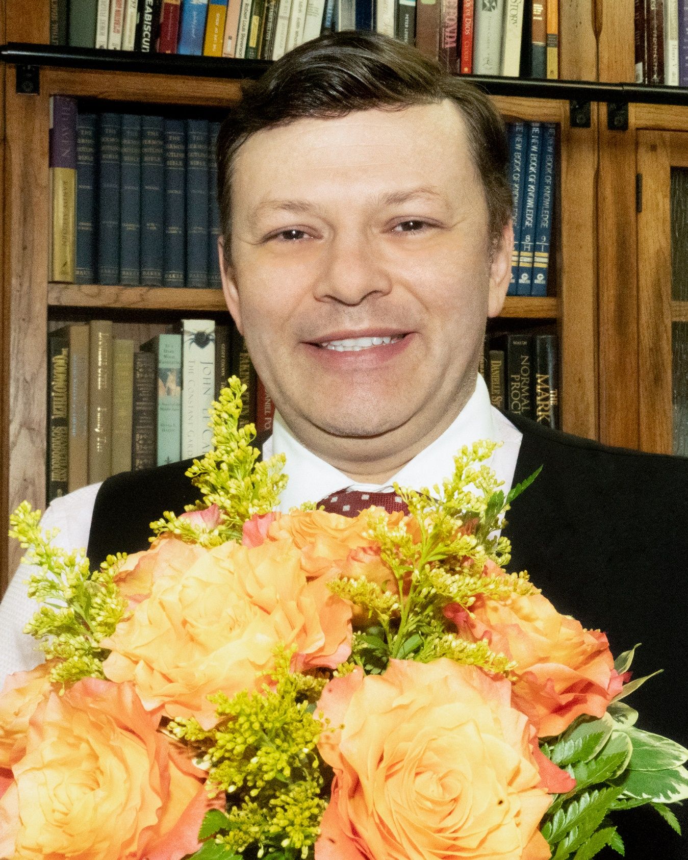 A person smiling with a bouquet of flowers Description automatically generated