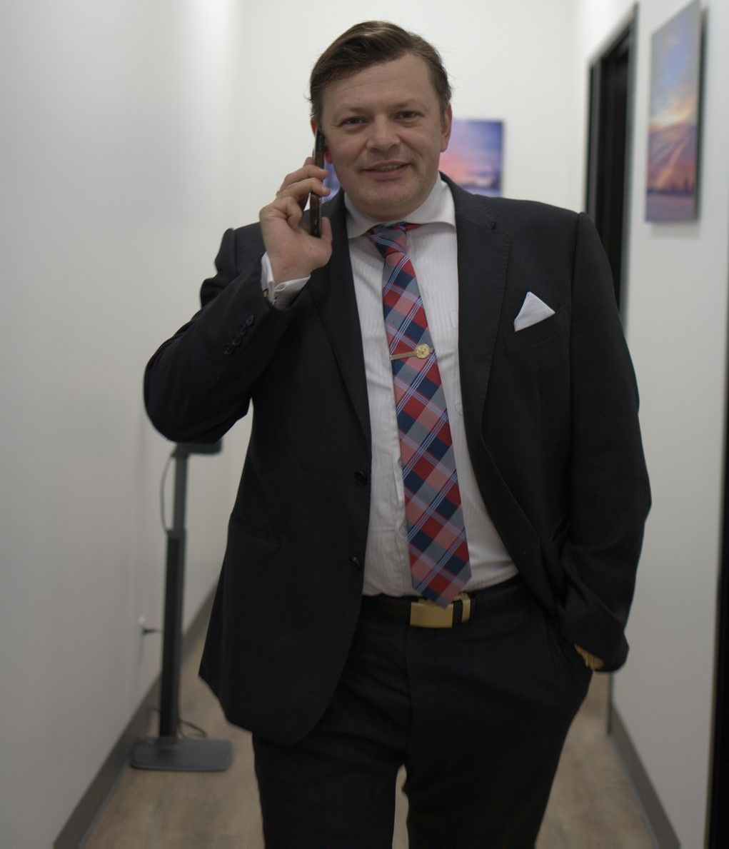 A person in a suit and tie talking on a cell phone Description automatically generated