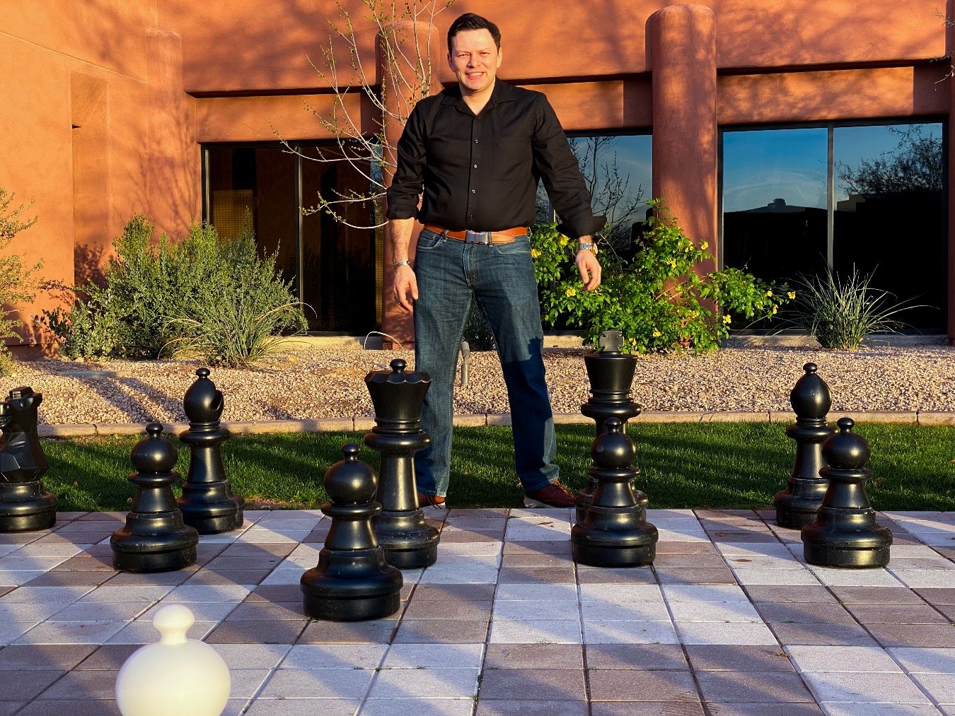 A person standing in front of a large chess board Description automatically generated