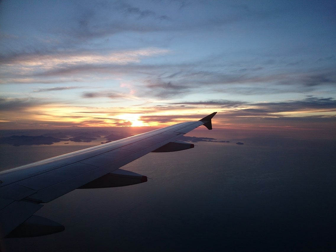 A sunset over marlborough sound, new zealand, with a plane's wing in the foreground.