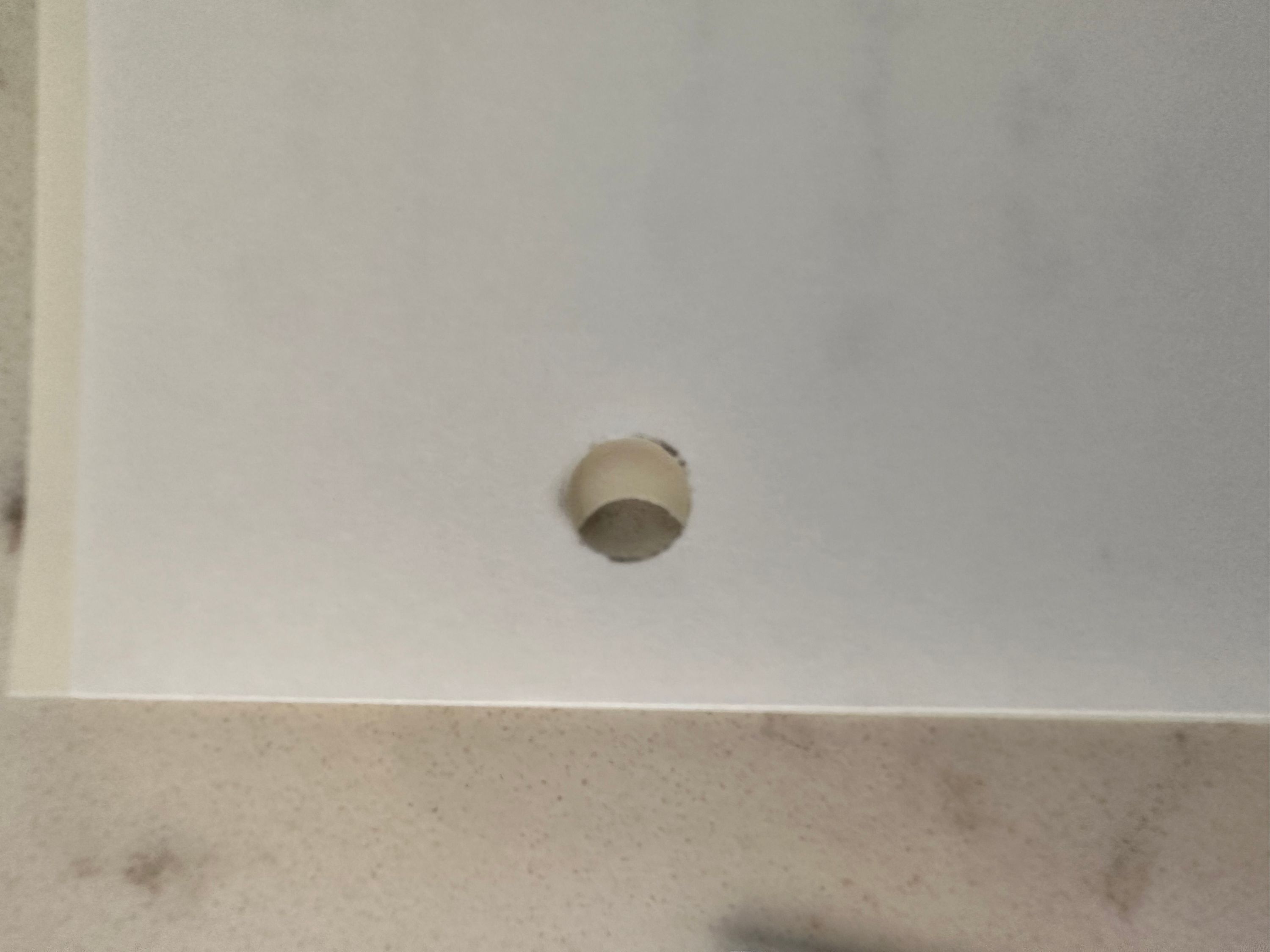 Two pieces of paper with holes punched in them, stacked to show the one eighth inch difference in how far the holes are inset from the edge of the page