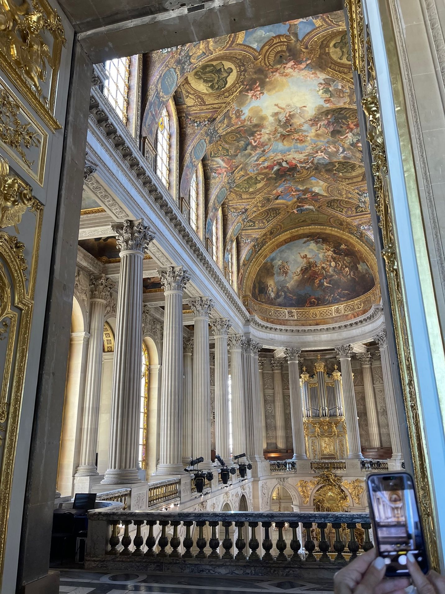 A large ornate building with gold ceiling and painting with Chapels of Versailles in the background AI-generated content may be incorrect.