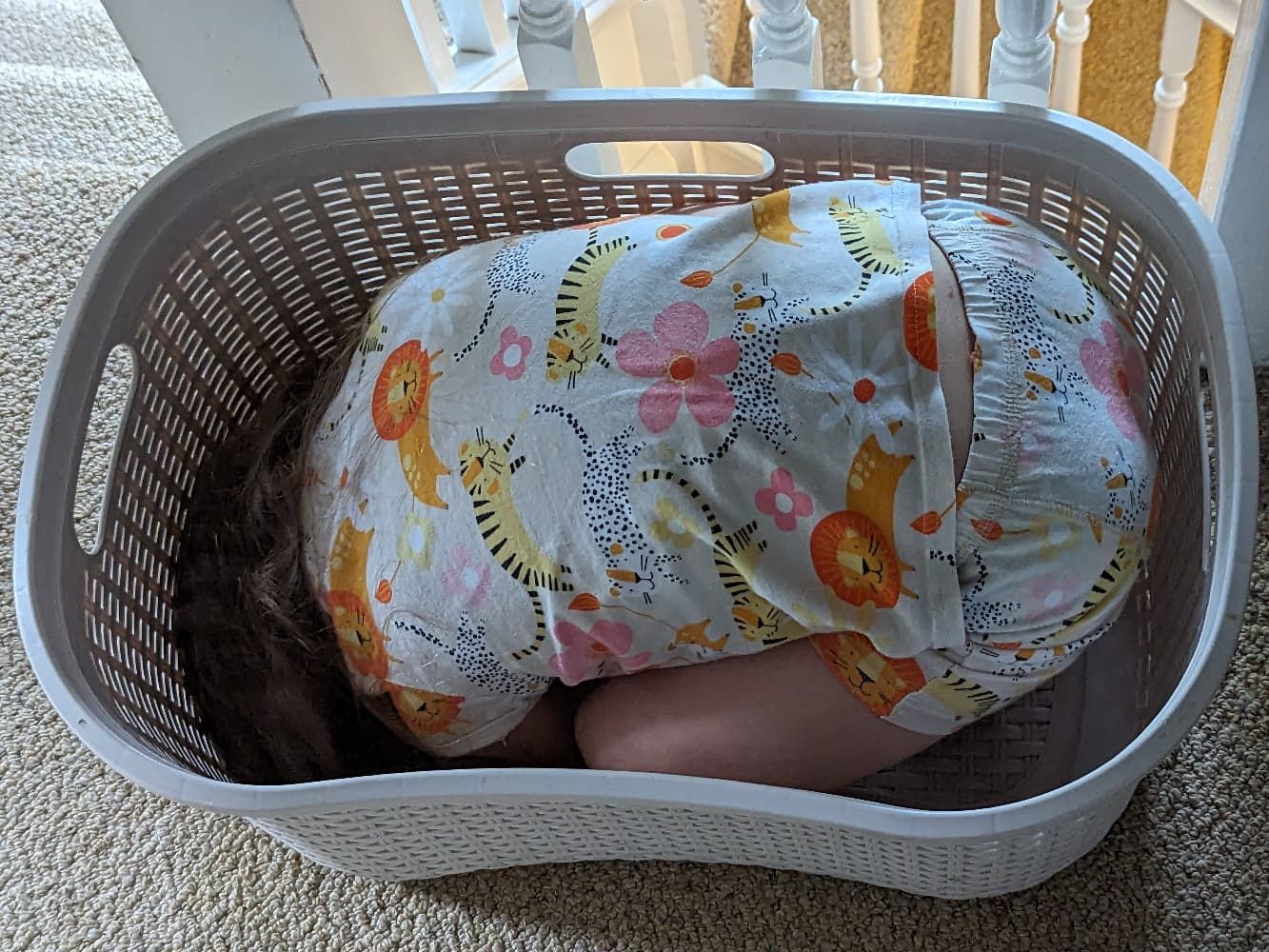 A small child hiding in a laundry basket