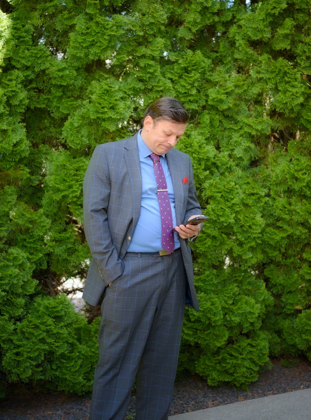 A person in a suit looking at his phone Description automatically generated