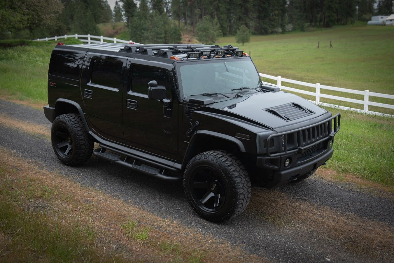 A black car parked on a gravel road Description automatically generated