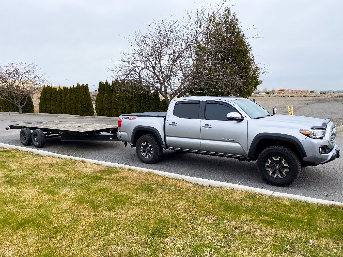 A truck towing a flatbed trailer Description automatically generated