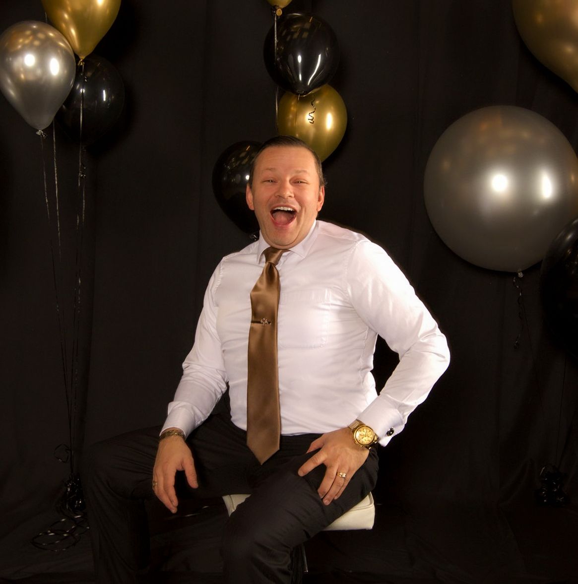 A person sitting on a chair with balloons in the background Description automatically generated