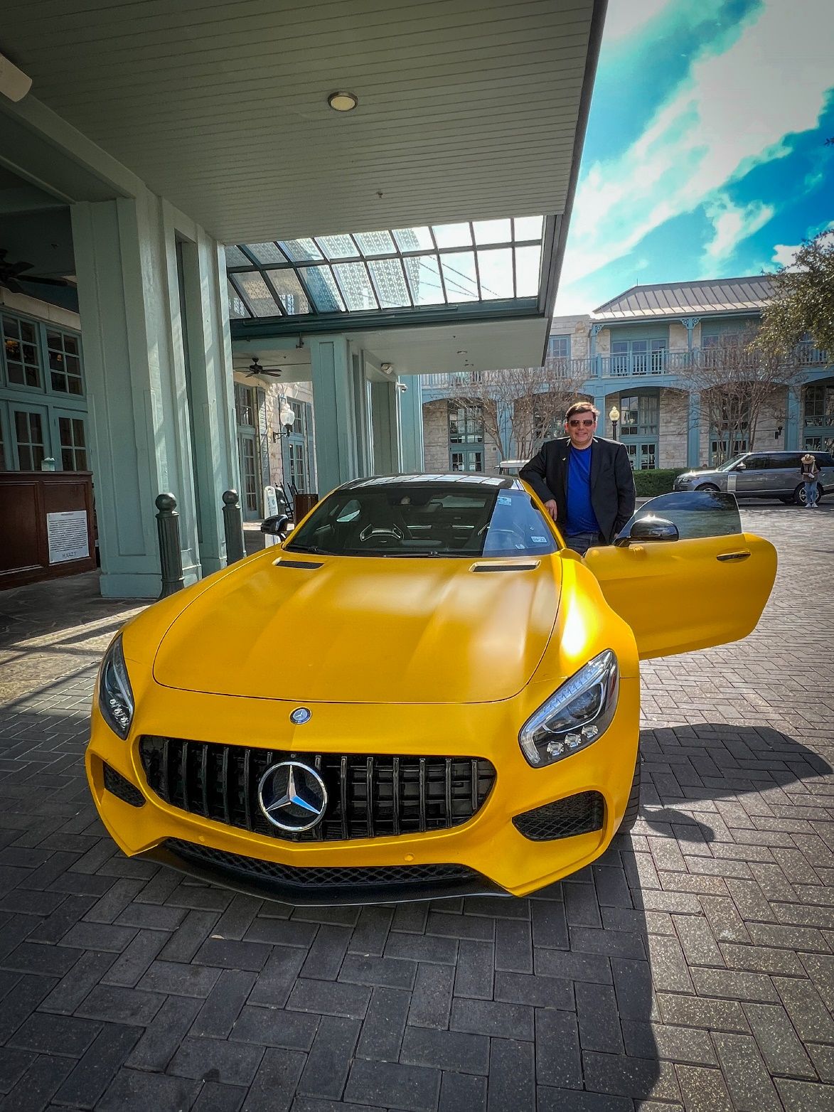A person standing next to a yellow sports car Description automatically generated