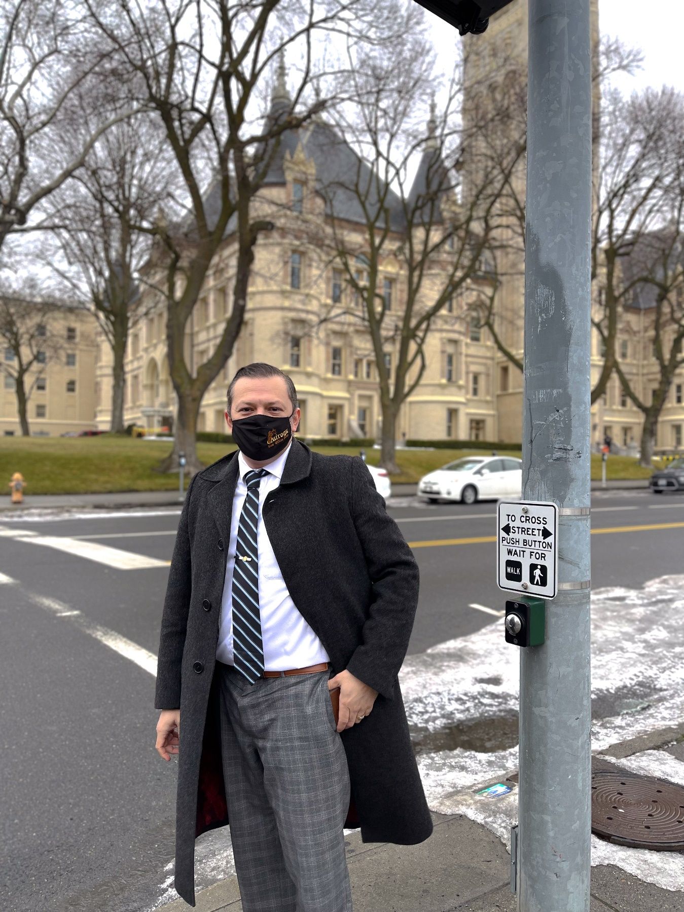 A person wearing a face mask standing on a street corner Description automatically generated