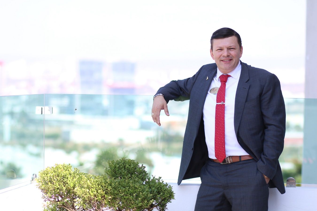 Un hombre en traje posando para una foto Descripción generada automáticamente