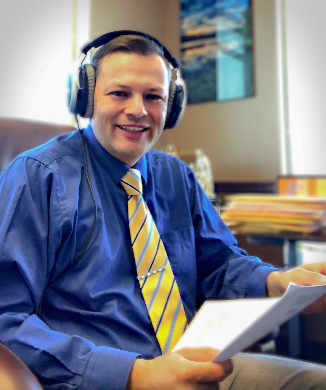 A person wearing headphones and a blue shirt and yellow tie Description automatically generated