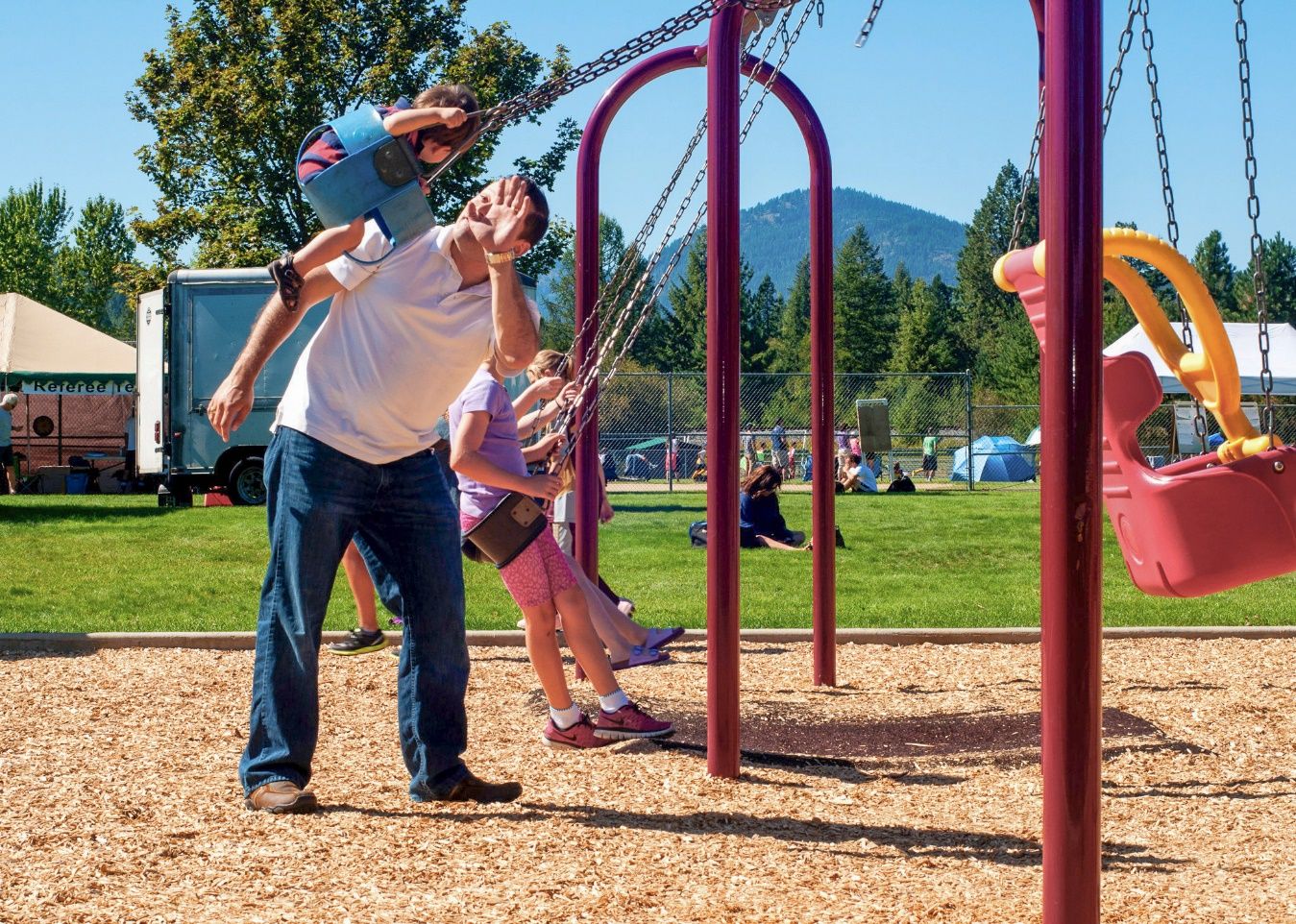 A person and children playing on a playground Description automatically generated