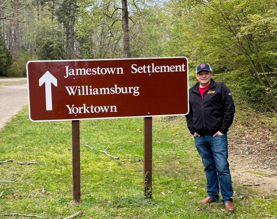 A person standing in front of a sign Description automatically generated