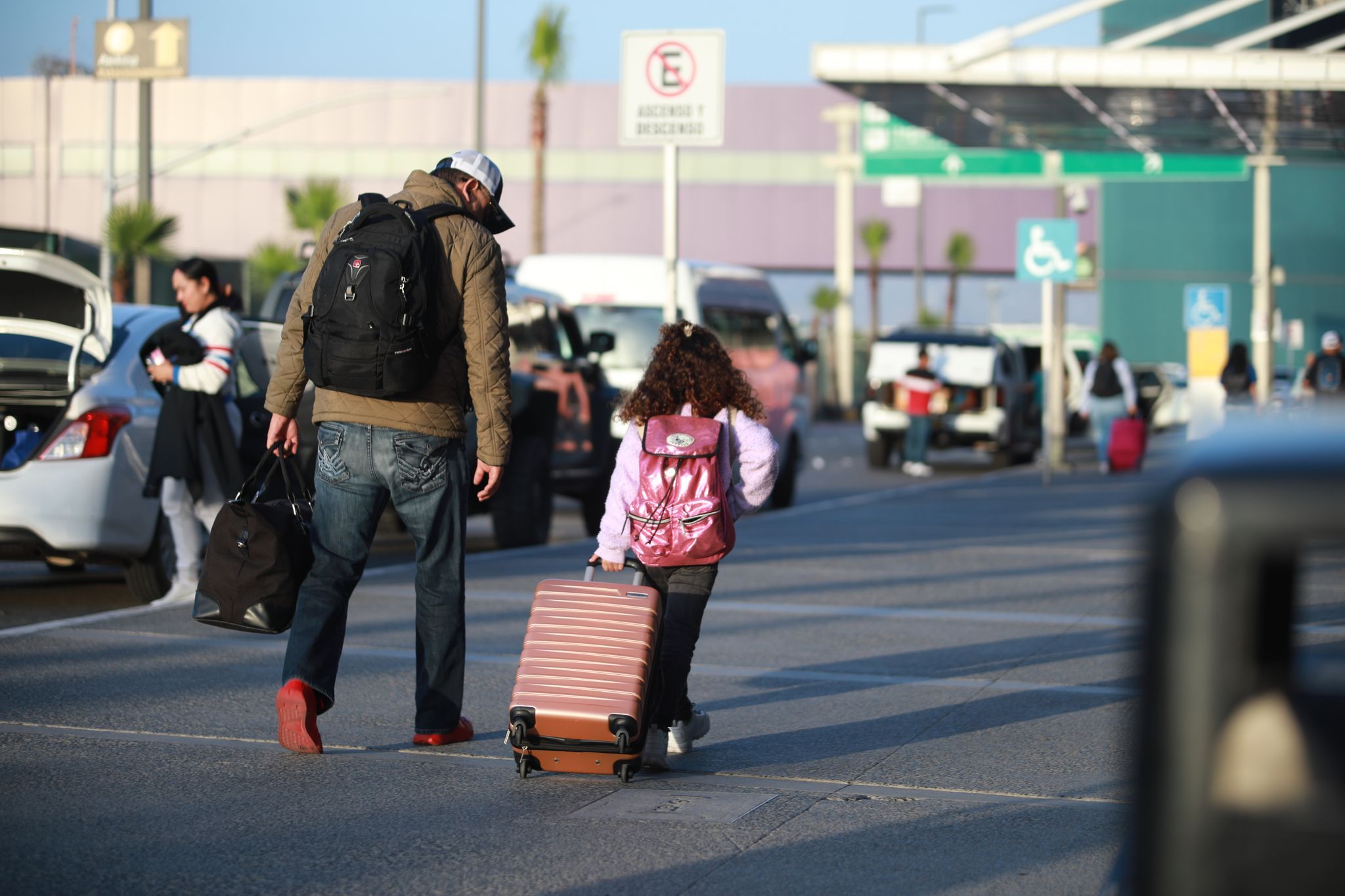 A person and a child pulling luggage Description automatically generated