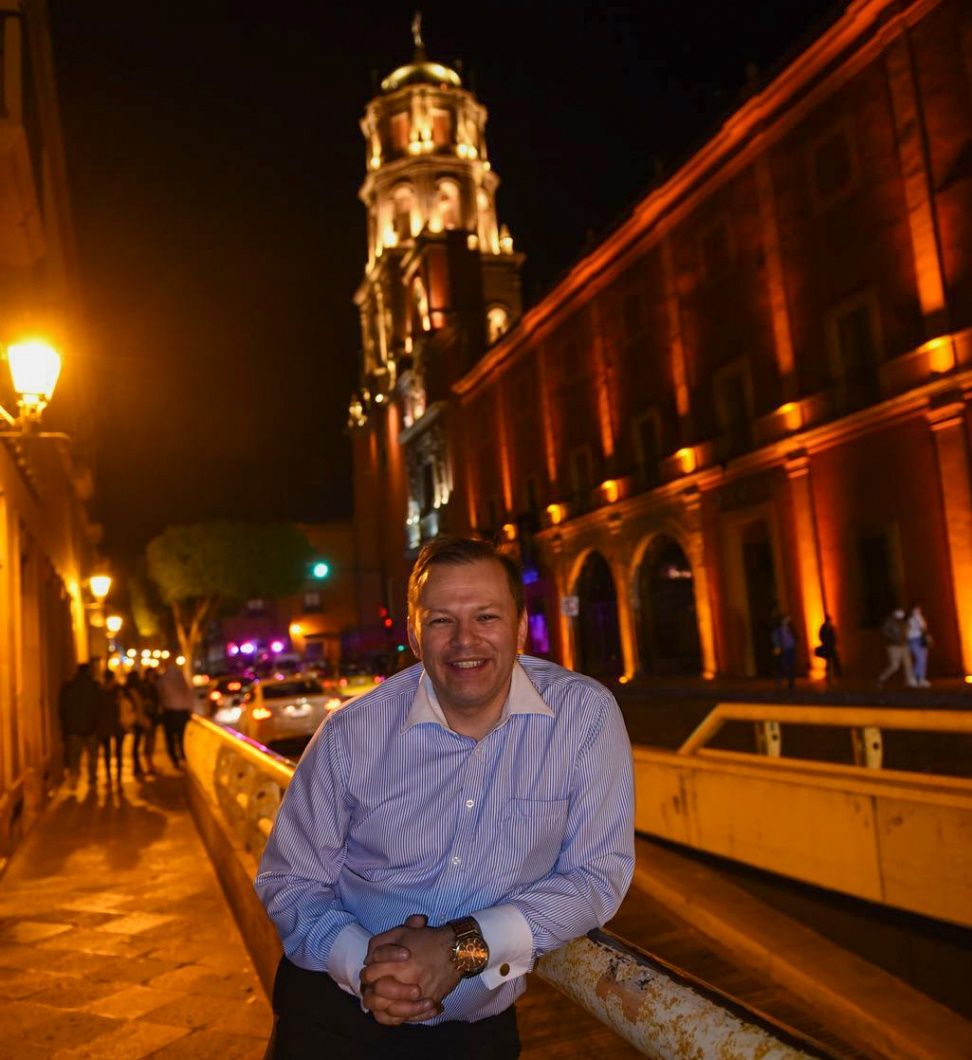 A person sitting on a railing in front of a building Description automatically generated