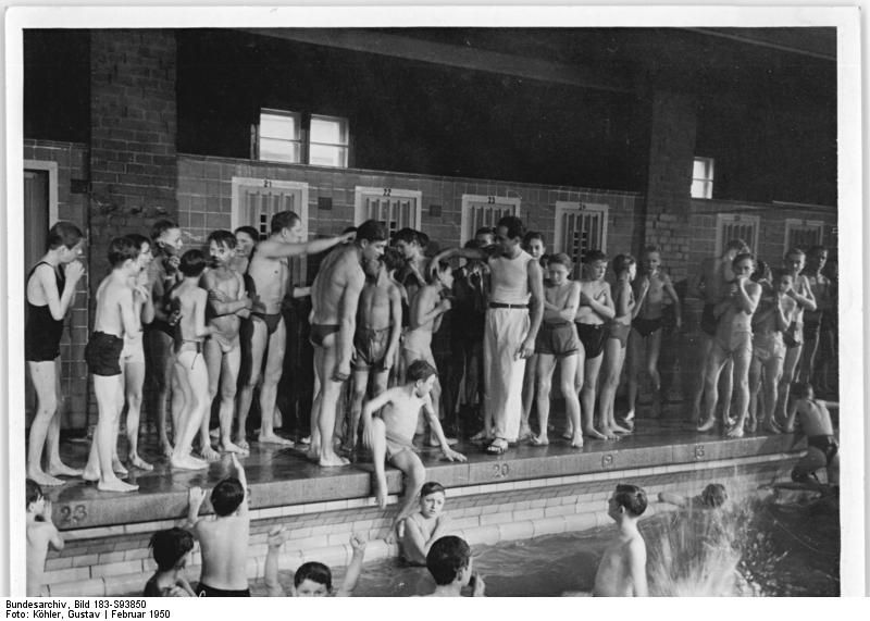 „Bundesarchiv Bild 183-S93850, Berlin-Lichtenberg, Schwimmbad, Bademeister“ von Köhler, Gustav - Dieses Bild wurde im Rahmen einer Kooperation zwischen dem Bundesarchiv und Wikimedia Deutschland aus dem Bundesarchiv für Wikimedia Commons zur Verfügung gestellt. Das Bundesarchiv gewährleistet eine authentische Bildüberlieferung nur durch die Originale (Negative und/oder Positive), bzw. die Digitalisate der Originale im Rahmen des Digitalen Bildarchivs.. Lizenziert unter CC-BY-SA-3.0-de über Wikimedia Commons.