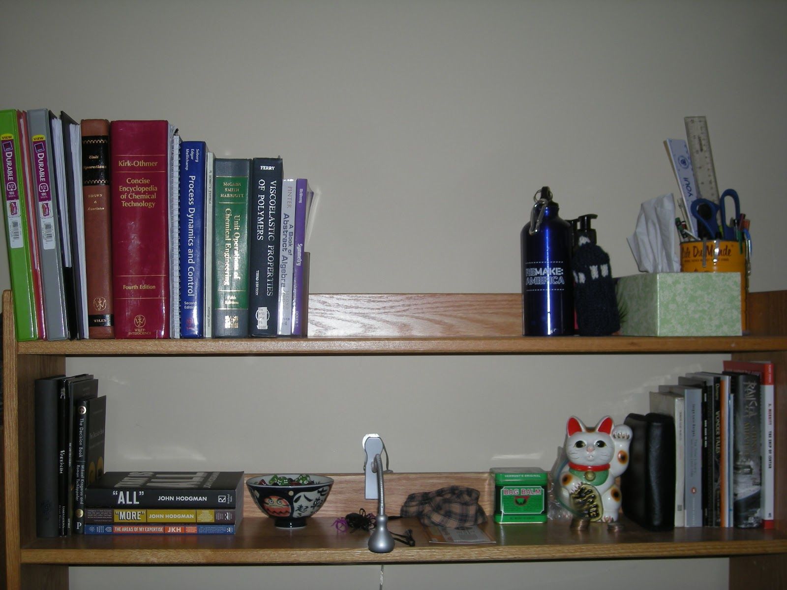 Two sparse shelves from a college dorm with a handful of books in each corner and some knick-knacks in the middle of each shelf.