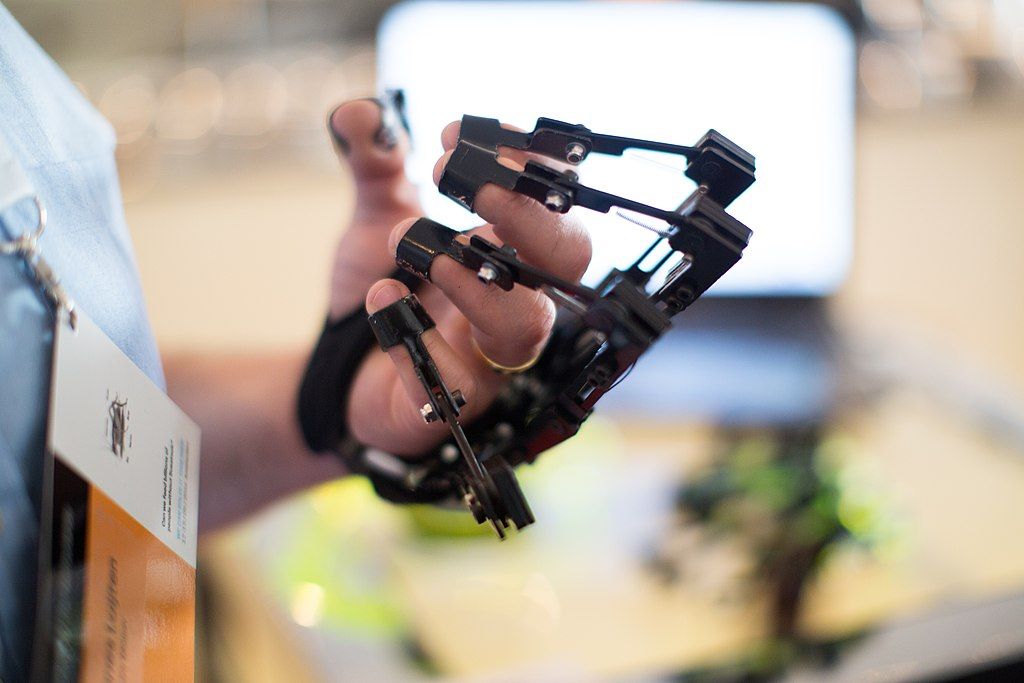 A curled hand hearing an articulated mechanical frame around it, as if for input.
