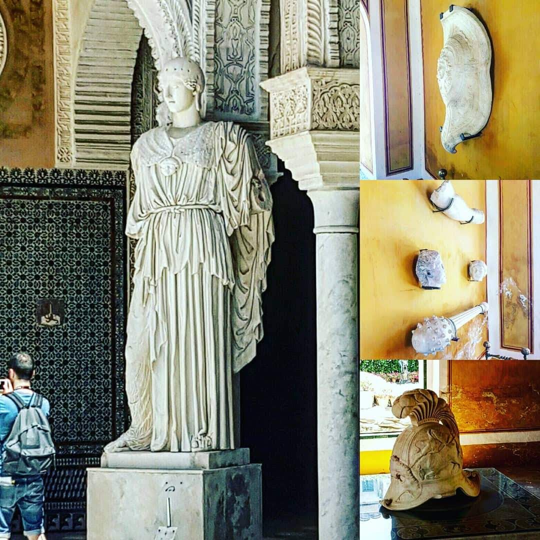 A partial statue of Athena stands in a courtyard. In collaged images, her shield, mace, and helm are shown, distributed throughout the rest of the palace.