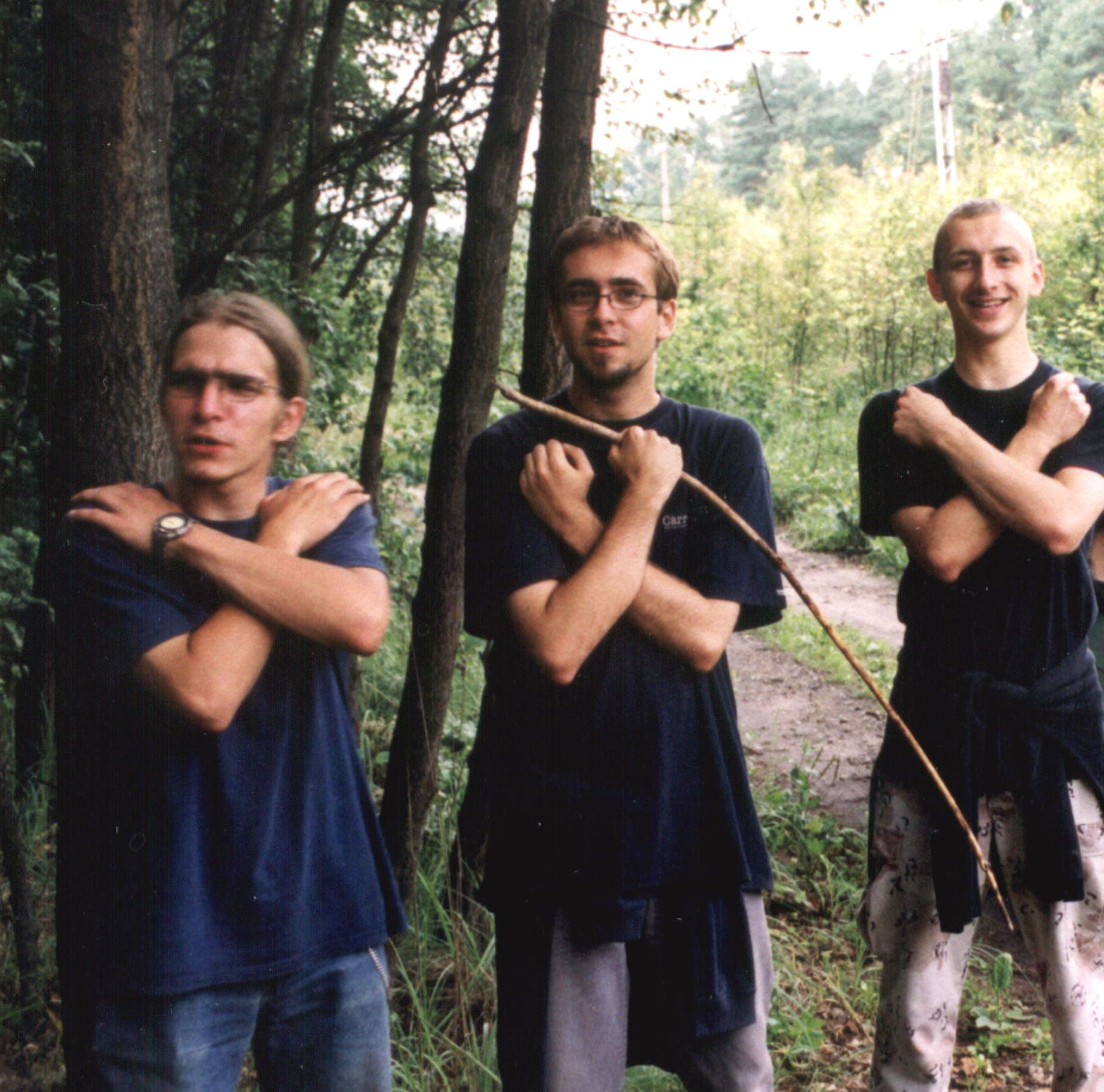 A photo of three plainclothes LARPers in Poland, maybe. They are crossing their arms across their chests to represent invisibility.