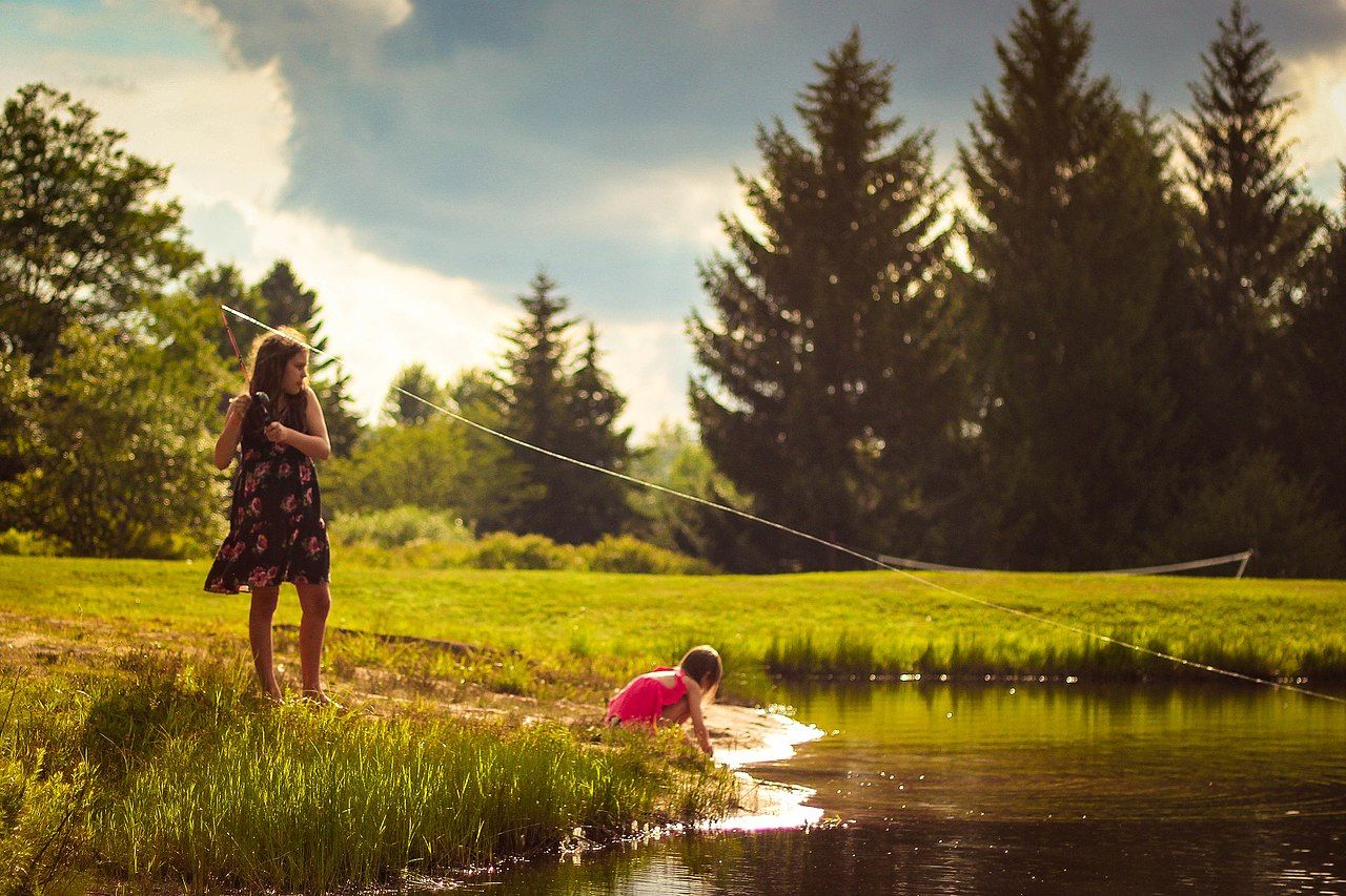 Two female children by a pond in Timberline Four Seasons Resort attempting to catch fish.