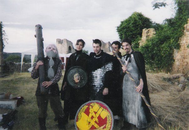 A photo of five medieval LARPers in Château de Couzan, France, 2004. They also pose for the camera, in front of some ruins.