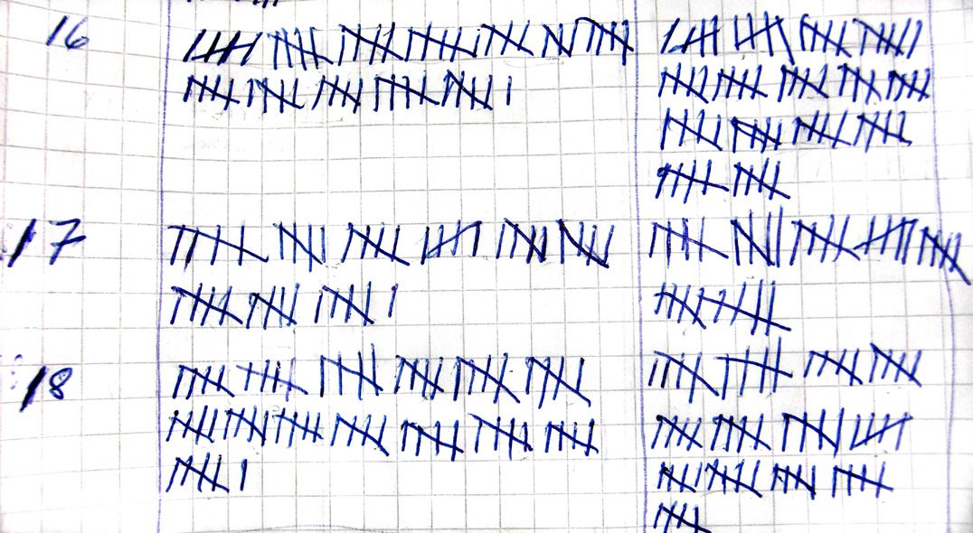 A sheet of graph paper covered in tally marks. From the source: Visitors being counted manually by using an unary numeral system. Note that different persons had made the tally marks, and that two of the groups of tally marks actually are wrong.