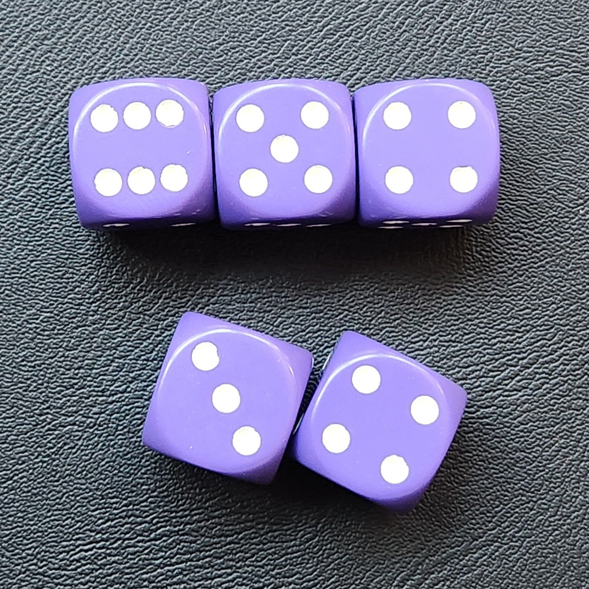 Five purple six-sided dice on a black (fake) leather surface, showing 6-5-4 in the top row and 3-4 in the bottom.