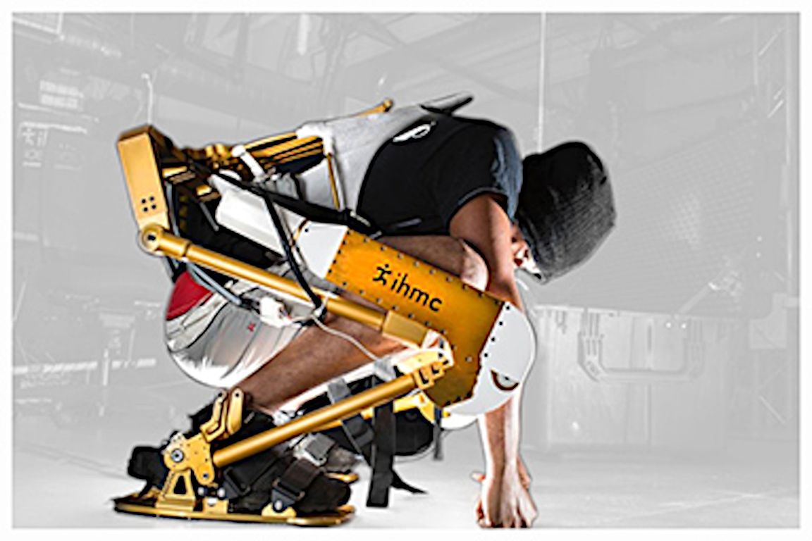 A man squats in profile, his legs eclipsed by a yellow brace with pistons.